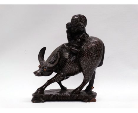 A Chinese carved hardwood, silver wire inlaid group of a boy on a water buffalo, height 27.5cm, length 21.5cm. 