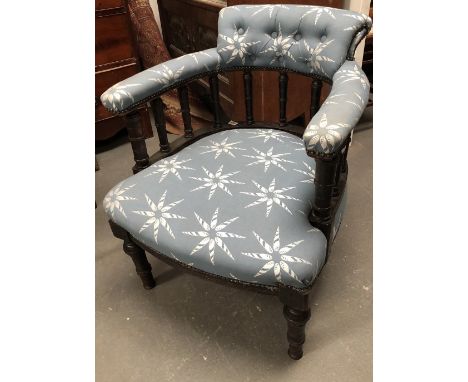 A late Victorian upholstered tub chair - An ebonised overstuffed, button back open armchair with turned front legs and suppor