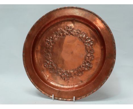 Hugh Wallis Arts and Crafts copper - An embossed copper charger with floral and foliate chaplet, planished ring and punchwork