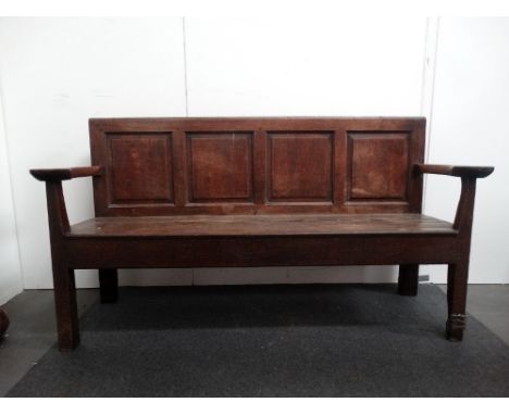 A 17th century oak four panel settle with open shaped arms and plank seat, height 92cm, width 169.5cm, depth 56cm. 