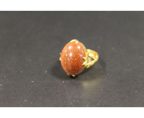AN INDISTINCTLY MARKED YELLOW METAL OVAL CABOCHON GOLDSTONE RING - APPROX WEIGHT 6 G