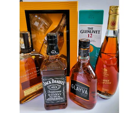 A group of bottles of whisky, Cognac, and liqueur, including Glenmorangie Highland single malt Scotch Whisky with two glasses