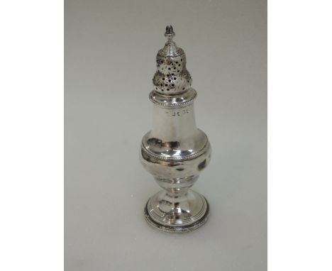 A Georgian silver caster of baluster form having gadrooned decoration, pierced lid and pineapple finial, London 1792, Thomas 