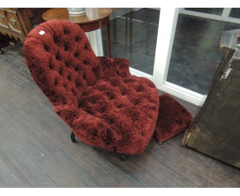 A Victorian style tub armchair having button down burgundy upholstery and a similar footstool
