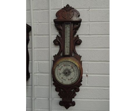 An Edwardian oak cased aneroid barometer having carved decoration, marked Rhodes, Kendal