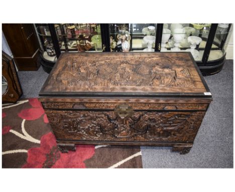 Early 20thC Chinese Camphor Chest profusely carved to hinged top, front and sides depicting home life figures, buildings and 