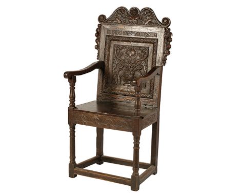 CHARLES II OAK WAINSCOT CHAIR with a serpentine cresting carved with the figure of a green man and the ears with heraldic bea