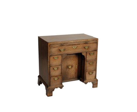 A GEORGE II MAHOGANY KNEEHOLE DESK, the caddy top with a simple moulded edge over a slide and an arrangement of seven drawers