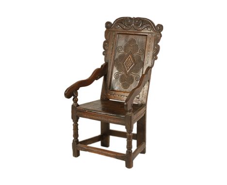 CHARLES II OAK WAINSCOT ARMCHAIR, basically 17th century, with a carved cresting and ears over a panel carved with a lozenge 