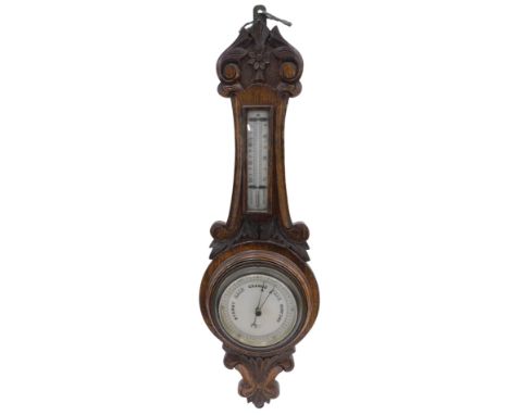 A late 19thC/early 20thC carved oak aneroid barometer and thermometer, the dial stamped W Mansell of Lincoln, 66cm high. 