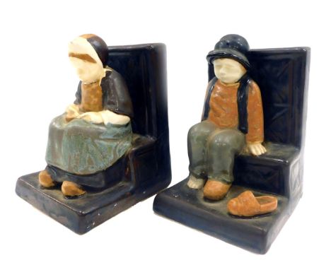 A pair of Berthe Savigny for Grand Maison HB Faience bookends, depicting male and female figures seated, on a step, 17cm high