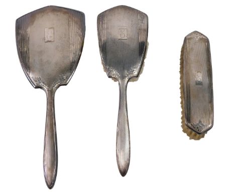 A silver mounted three piece engine turned brush set, in art deco style, comprising mirror, hand brush and clothes brush, eac