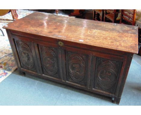 A 17TH CENTURY OAK COFFER  the panelled front carved with two pairs of portrait heads, 145cm wide 62cm deep 74cm high