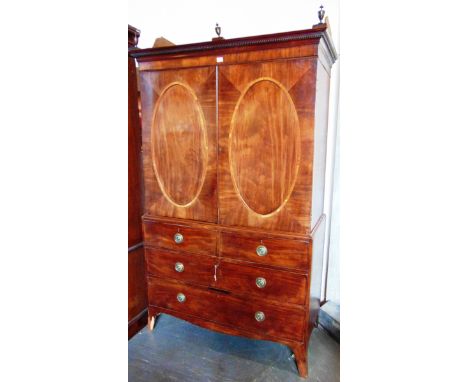 A GEORGE III MAHOGANY LINEN PRESS  adapted, with dentil frieze surmounted by three vase shaped finials, above pair of doors w