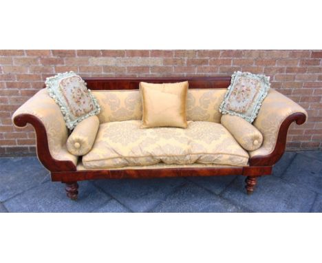 A MAHOGANY FRAMED RE-UPHOLSTERED SOFA in the Empire taste, with scroll arms on turned supports with brass casters, 215cm wide
