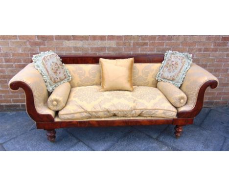 A MAHOGANY FRAMED RE-UPHOLSTERED SOFA in the Empire taste, with scroll arms on turned supports with brass casters, 215cm wide