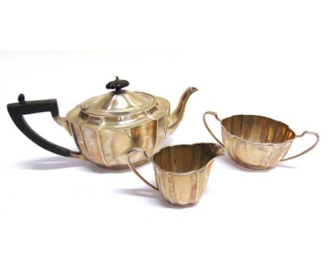 A SILVER SHAPED-OVAL THREE PIECE TEA SERVICE  the tea pot with a composition angular scroll handle and finial, the sugar bowl