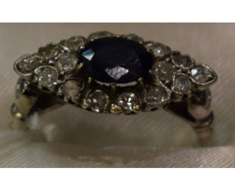 An Art Deco style diamond and deep blue sapphire effect doublet cluster ring, central deep blue stone surrounded by sixteen r