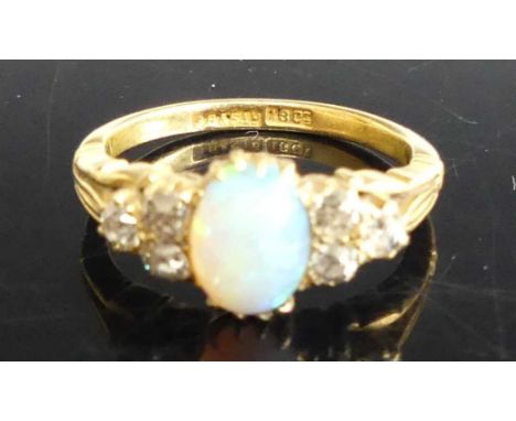 An 18ct gold, opal and diamond dress ring, the cabochon opal flanked to either side with three old round cut diamonds, total 