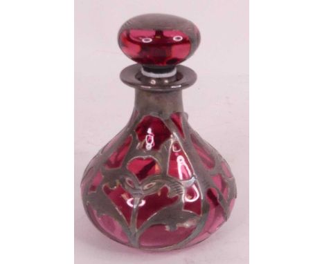 An Art Nouveau white metal overlaid cranberry glass bottle and stopper, height 11cmCracked around the neck.