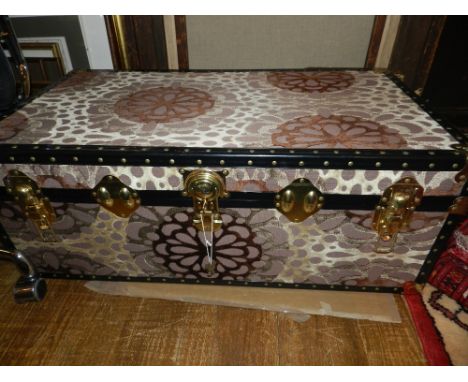A Contemporary steamer trunk, upholstered in a brown and cream fabric, having brass mounts.  H.35cm W.92cm D.50cm