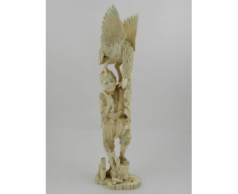 A Japanese Meiji period carved ivory okimono, a figural study of a falconer with bird of prey returning with catch, raised on