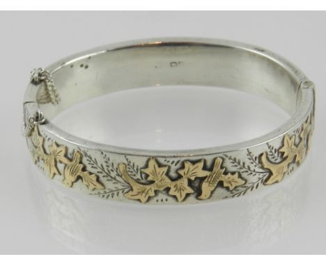 A silver bangle having applied bird and leaf decoration, hallmarked Chester. 