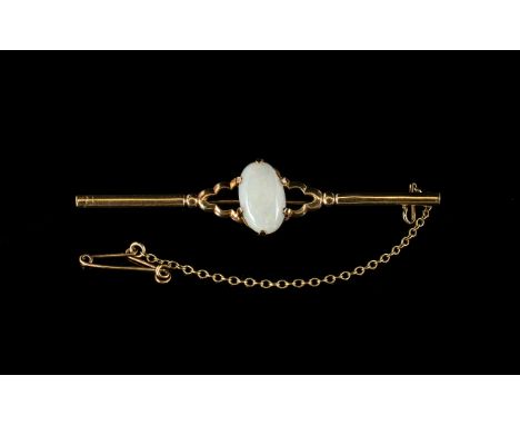 An Antique 9ct Gold Bar Brooch set with central oval milk opal. Fully hallmarked with safety chain.