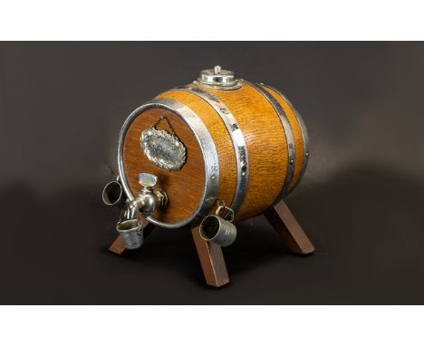 An Oak Scotch Barrel Dispenser with chrome banding.  Complete with small cups and a drip bucket underneath the tap, and a Sco