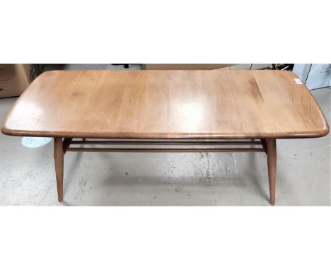 An Ercol light wood coffee table with shaped rectangular top and rail shelf under 