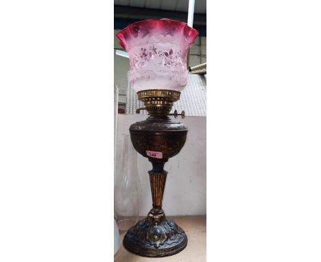 A Victorian brass oil lamp with cranberry shade Please note there is a hairline crack internally to lower body approx. 3cm 
