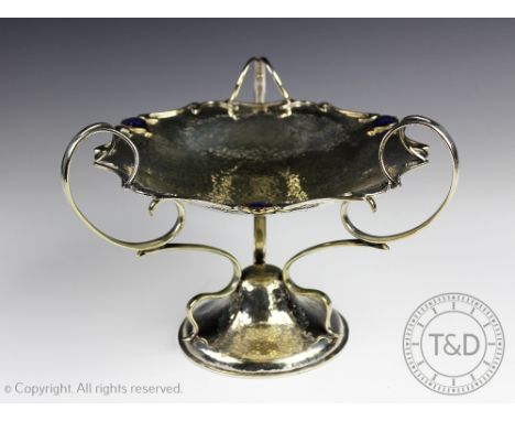 An Art Nouveau EPNS and enamel tazza, the concave bowl with three enamel plaques to the moulded rim raised upon three scroll 