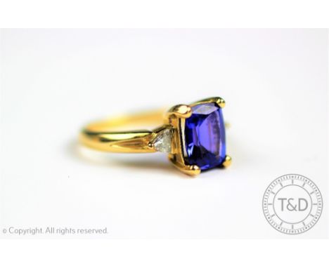 A tanzanite and diamond ring, the rectangular, mixed cut tanzanite flanked by a brilliant cut diamond to either side, all set