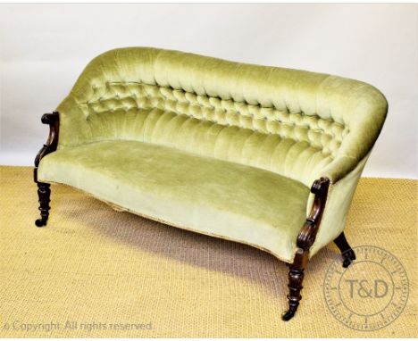 A William IV carved mahogany scroll end settee, of serpentine form, with button back green upholstery, on lappet carved legs 