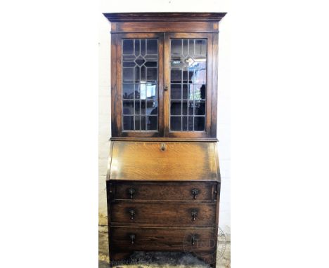 A 1920's oak bureau bookcase with two lead glazed doors above a fall and three long drawers, on bracket feet, 207cm H x 99cm 