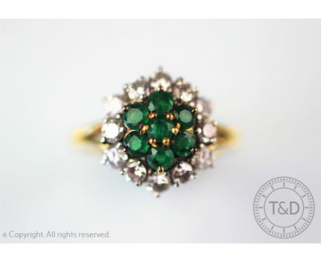 An emerald and diamond cluster ring, designed as a central seven stone emerald cluster and an outer surround of twelve brilli