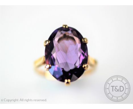 An amethyst set dress ring, the oval, mixed cut stone (measuring approx 16mm x 11mm) within six claw yellow metal setting (un