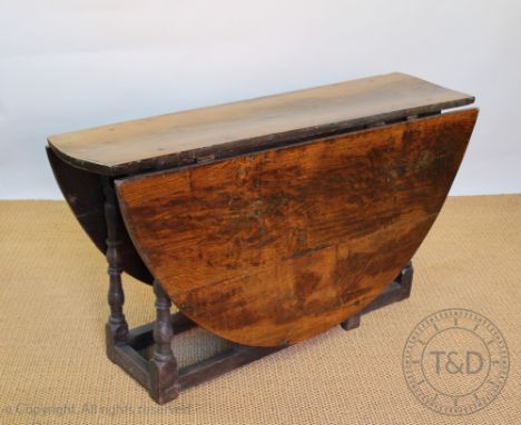 An 18th century oak gate leg table, the top and D shaped leaves  of a thick cut, on turned legs and stretchered base, 74cm H 