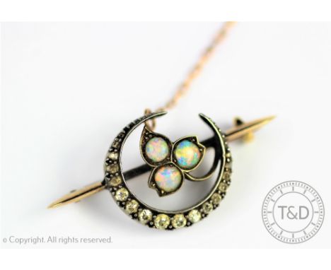 A Victorian opal and diamond brooch, designed as a diamond set crescent moon centred by an opal foliate cluster, upon a knife