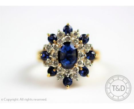 A sapphire and diamond cluster ring in 'snowflake' form, designed as a central oval sapphire within a diamond set surround an