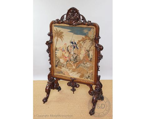 An impressive Victorian carved walnut fire screen, of country house proportions, the Berlin type tapestry panel decorated wit