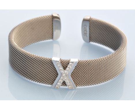 A Cede diamond and stainless steel bangle, the brilliant diamond set cross-form panel in 18ct. white gold mount on stainless 