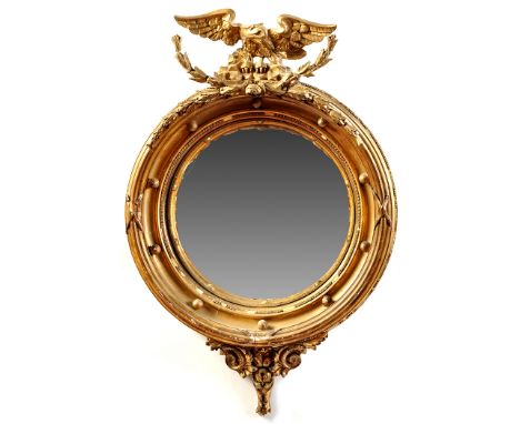 *A Regency giltwood convex wall mirror, the circular plate surrounded by lotus leaves, applied balls and ribbon and pole deco