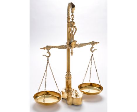 A pair of early 20th Century brass scales, the fish pattern arms hanging from bird pattern finial reeded stem, the base fitti