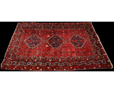 An early 20th Century Qashqai carpet, the triple diamond-shaped medallions surrounded by geometric floral motifs and scrollin