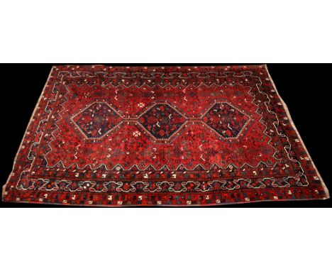 An early 20th Century Qashqai carpet, the triple diamond-shaped medallions surrounded by geometric floral motifs and scrollin