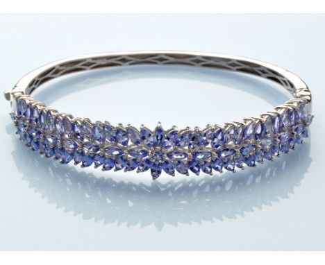 A tanzanite bangle, the top half set with marquise cut tanzanites in silver mount, single diamond set to underside, 7.5cms wi