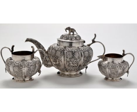 An Indian white metal three piece tea service, each piece of fluted melon form and profusely embossed with panels depicting e