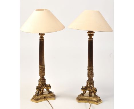 *A pair of 20th Century lacquered brass table lamps, the cream covered shades above acanthus and wreath pattern light fitting