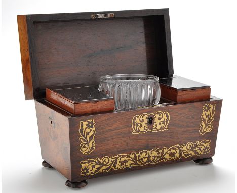 A Regency brass inlaid rosewood tea caddy, of sarcophagus form, with leaf scroll decoration, the cover opening to reveal a ce